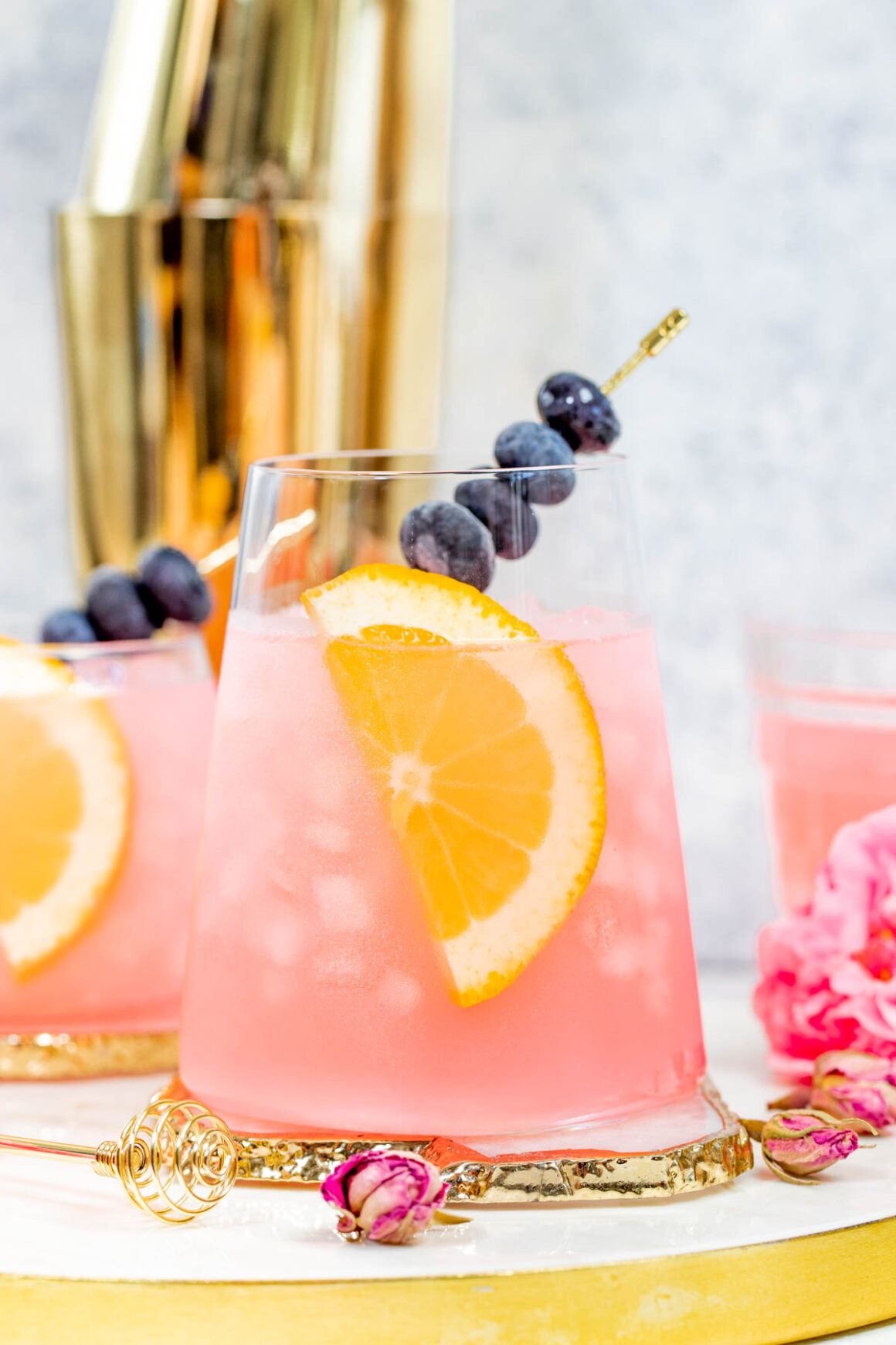 rose cocktail recipe with a orange piece and blueberries as a garnish 