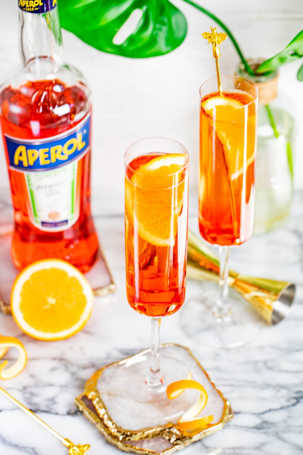 2 champagne glasses with limoncello cocktails and a red bottle of aperol liqueur