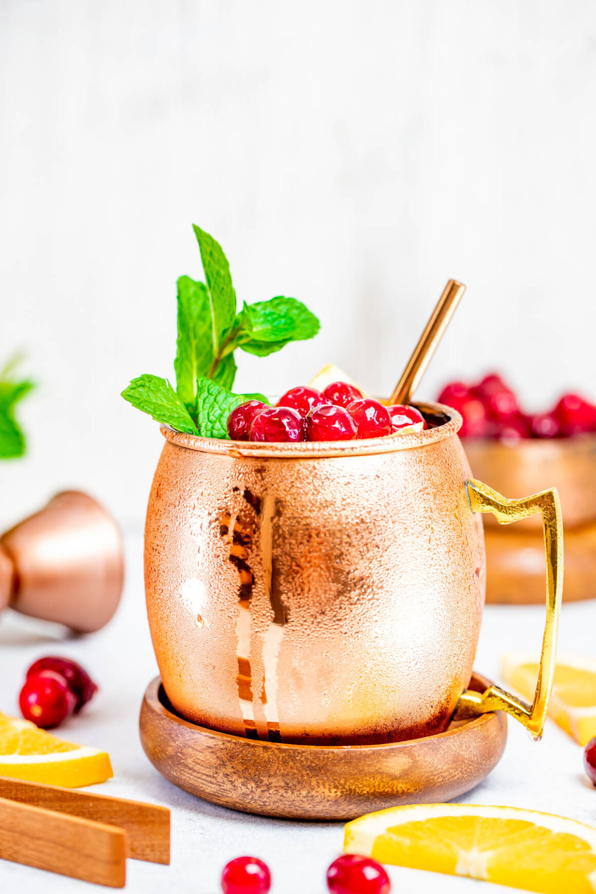 1 copper mug with a cranberry moscow mule garnish with fresh cranberries and sprig of mint