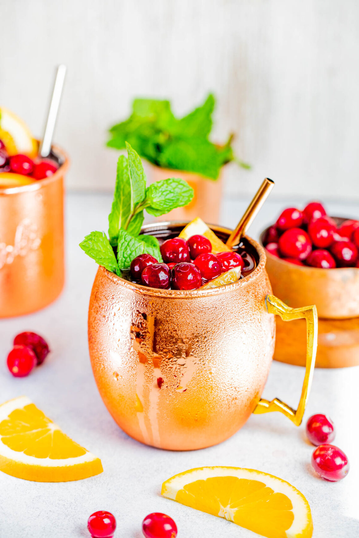vibrant photo of a cranberry moscow mule cocktail garnish with sprig of mint a cranberries