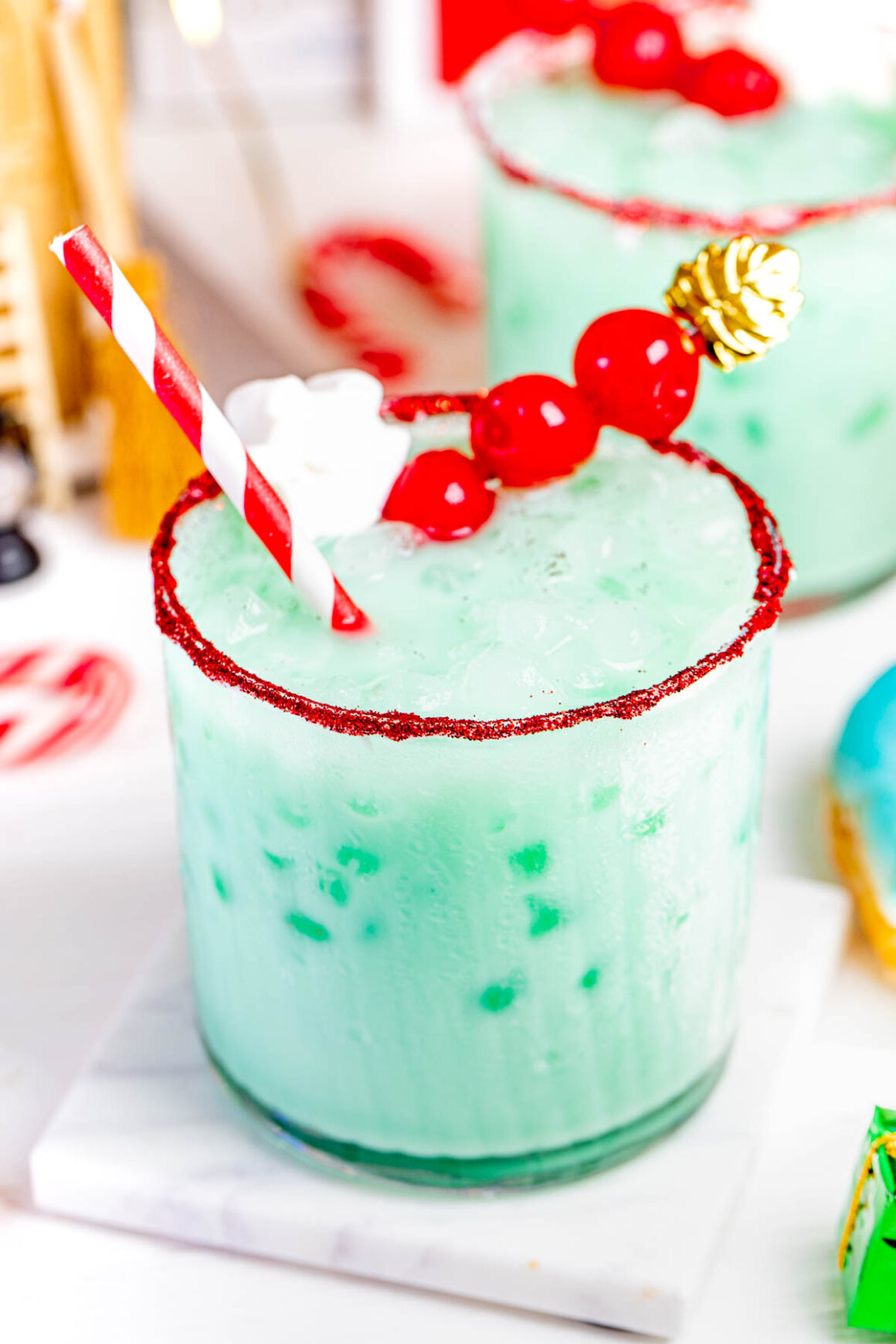 grinch recipe drink served in a short glass with a few cherries on top
