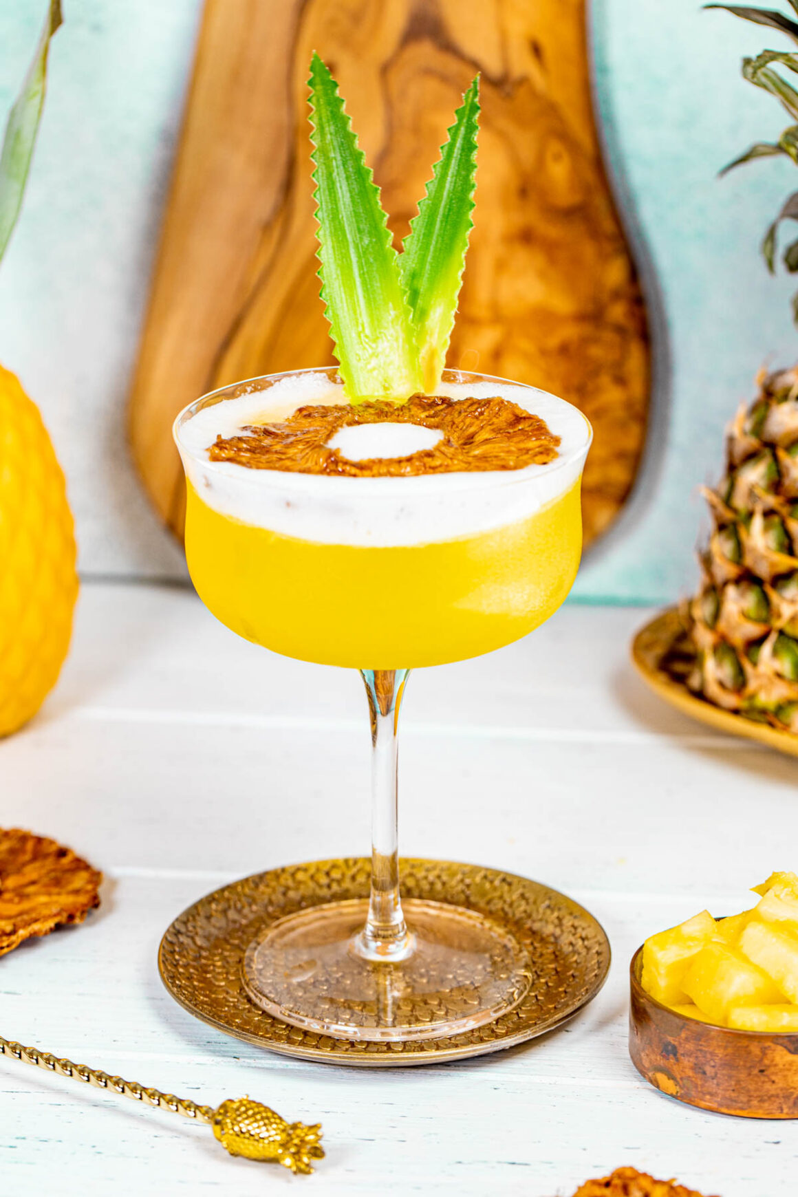coctel served in a martini glass with pineapple leaves as a garnish
