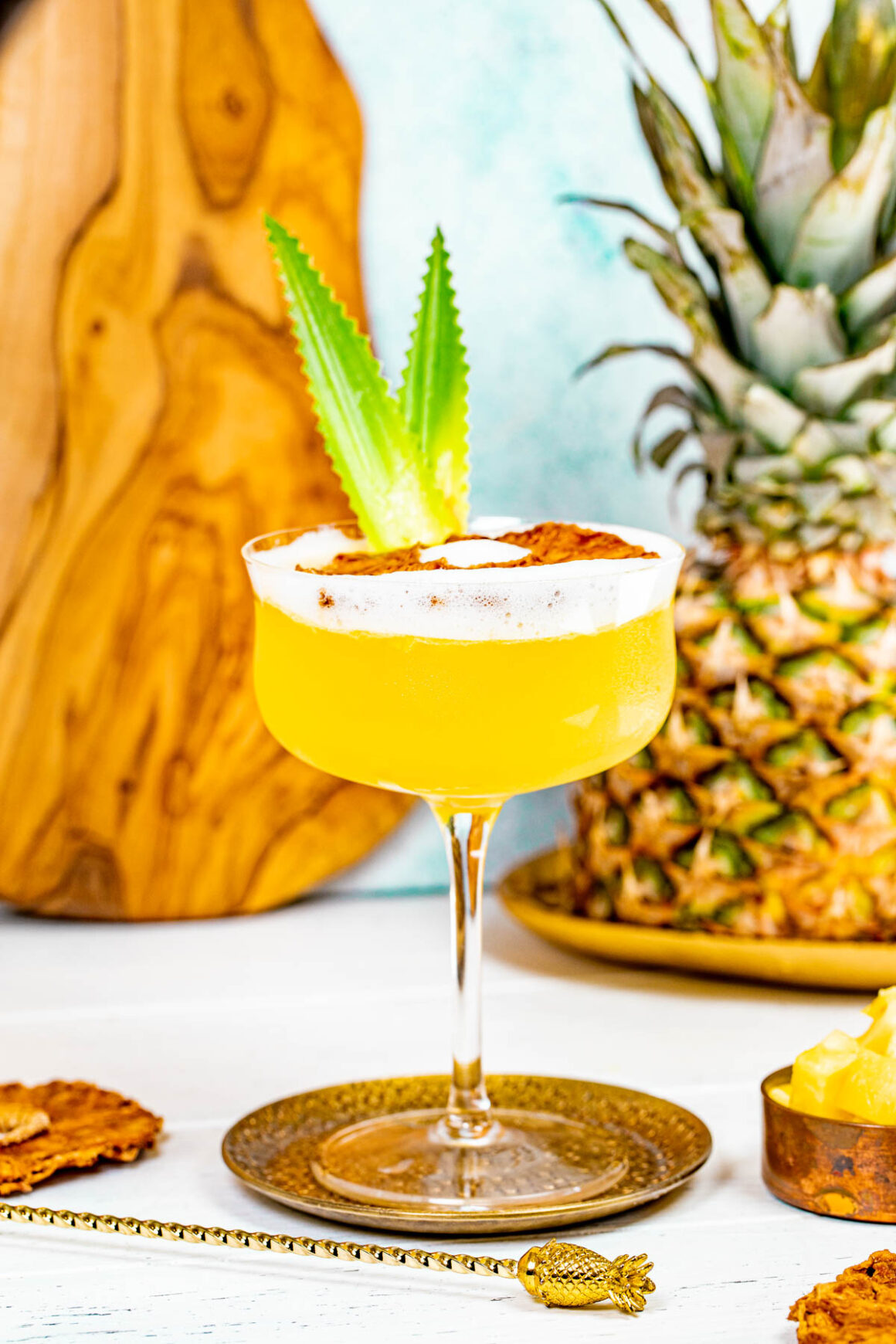 front view of a pineapple martini with a fresh pineapple on the background